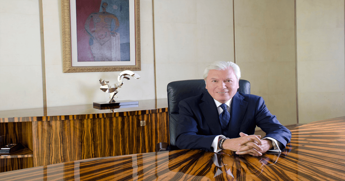 Carlos Hank Rhon portando traje sentado en oficina elegante