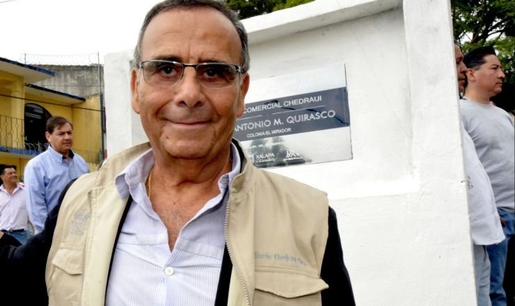 Alfredo Chedraui Obeso sonriente frente a un muro con un letrero de Comercial Chedraui, durante un evento público