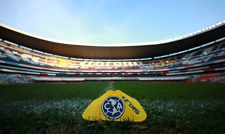 Marcador de entrenamiento amarillo con el isologo del Club América sobre césped del Estadio Azteca